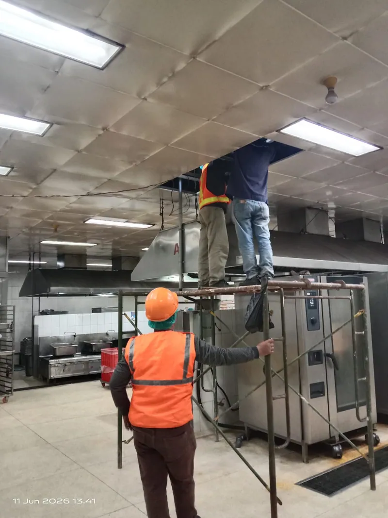 Engineering & Installation — Tim instalasi perpipaan bekerja dari perancah untuk memasang jalur di plafon dapur produksi