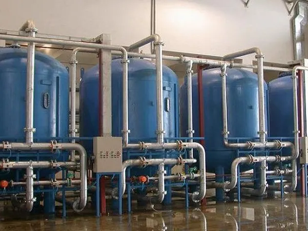 Multi-Media Filter & Water Softener — Deretan pressure vessel filter multi-media dan water softener dengan manifold pipa dan valve di ruang utilitas